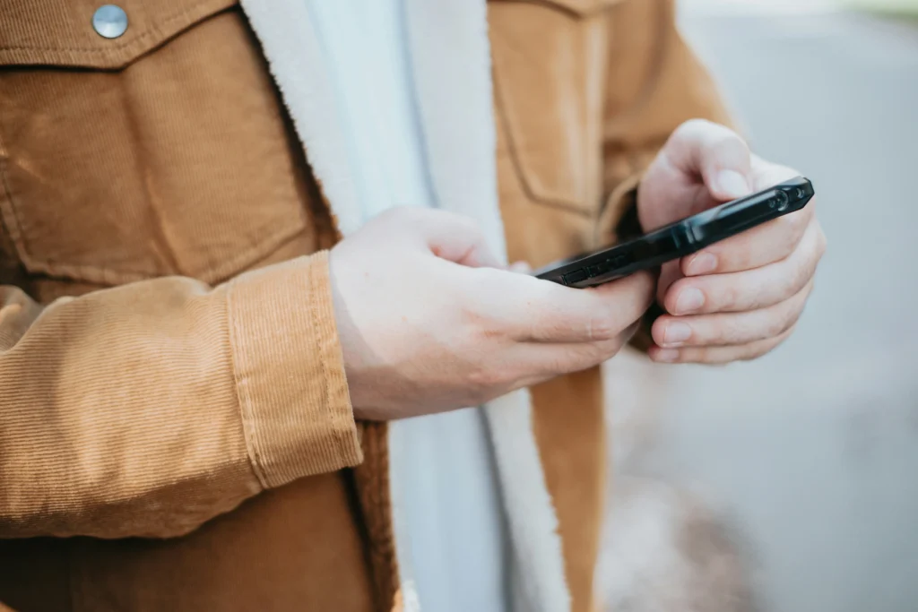 Close-up of hands holding a phone outdoors calling a sexual abuse attorney