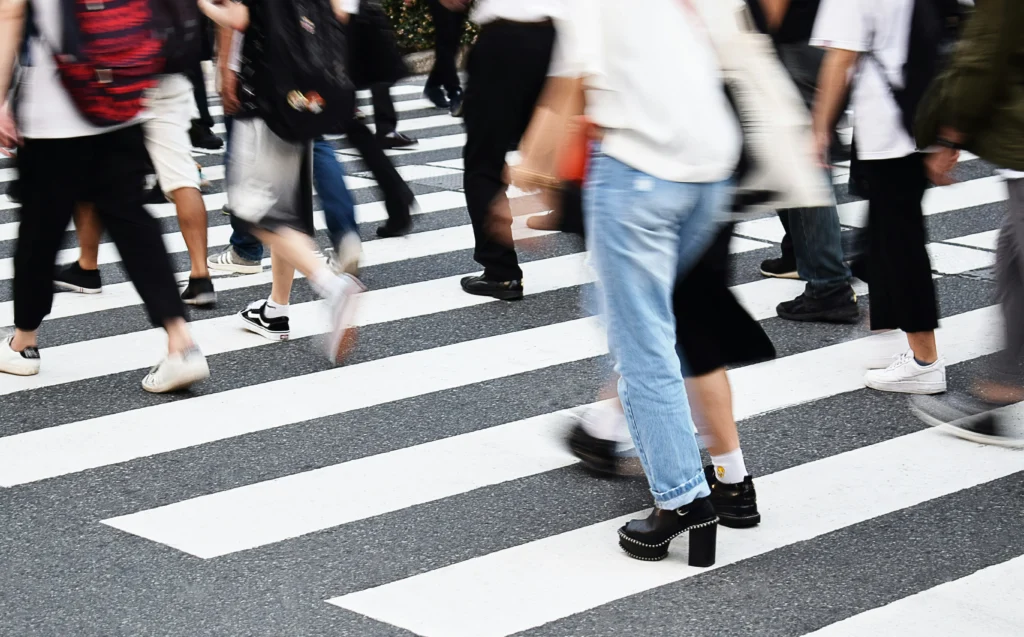 Crowds walking across a city crosswalk, showing why a Chicago pedestrian accident lawyer’s guidance is essential