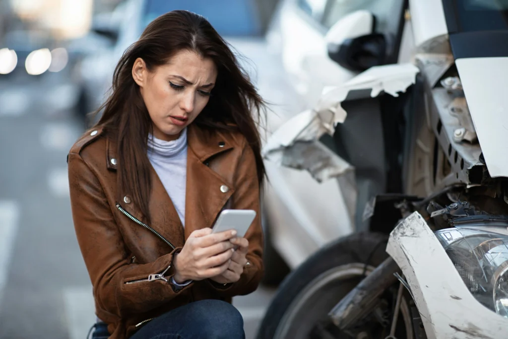 Woman sitting near a damaged car after an accident calling a Chicago Brain Injury Lawyer for legal help