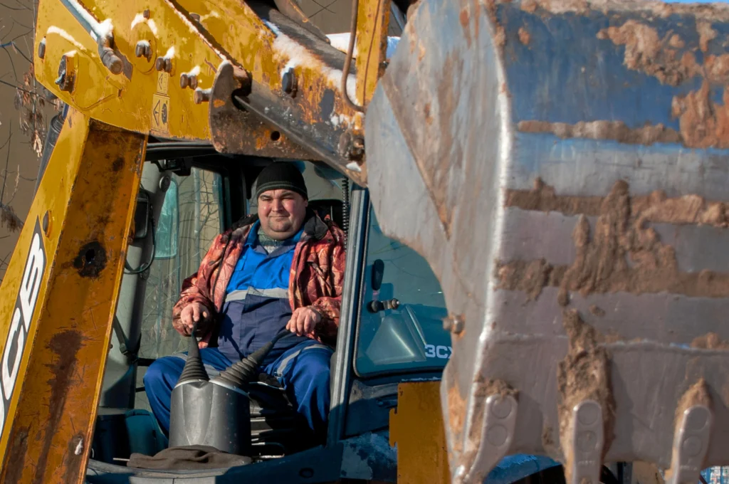 Construction worker driving excavator at job site