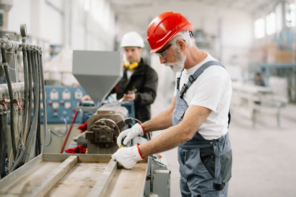 Factory worker using heavy machinery, illustrating risks tied to tendonitis workers' compensation settlements.