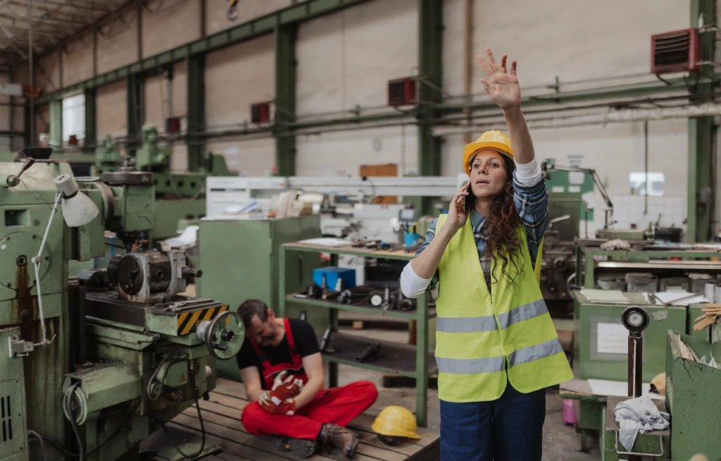 Female worker on phone raising hand during workplace accident