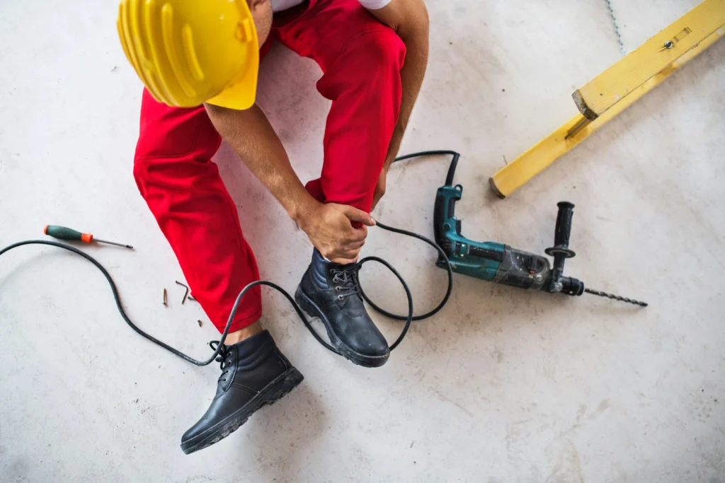 Injured construction worker holding ankle after job site accident in need of illinois worker comp lawyer