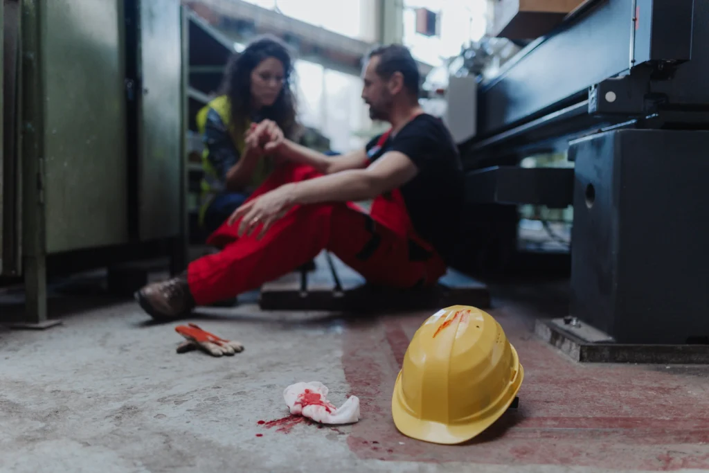 Man bleeding from head injury at work with safety helmet on floor
