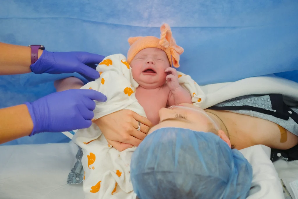 Mother holding newborn with nurse assistance