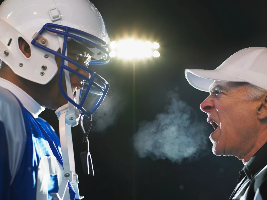 Football player being yelled at by coach during game; example of coaching negligence handled by a sports injury lawyer.