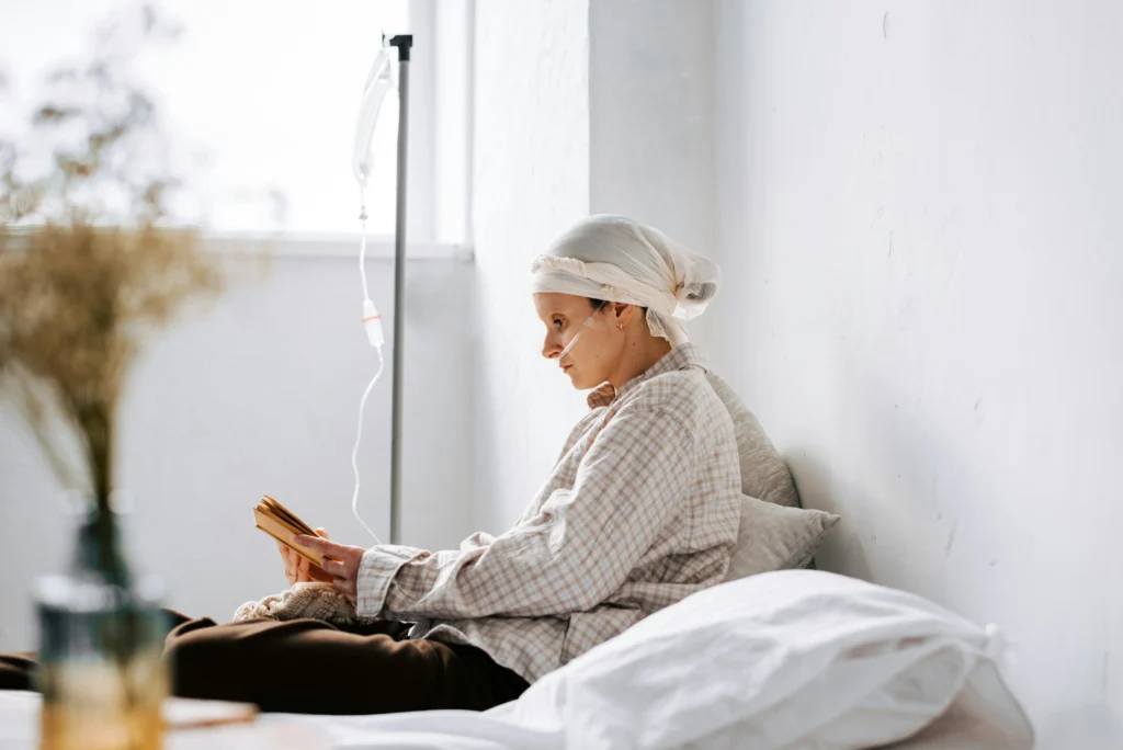 Patient receiving IV treatment and reading, highlighting the role of a cancer misdiagnosis lawyer in her case.
