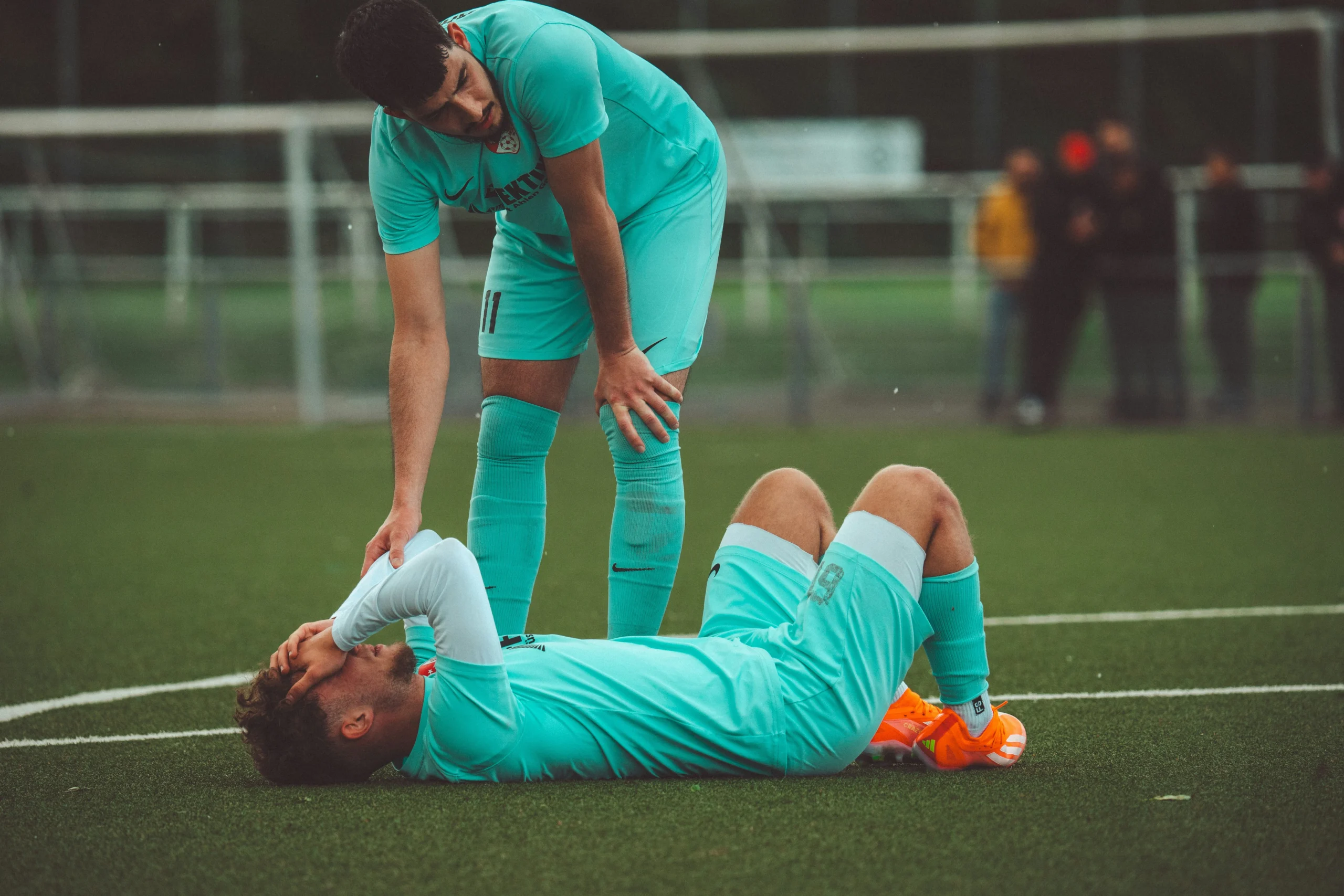 Soccer player injured on field with teammate’s support and need for sports injury lawyer