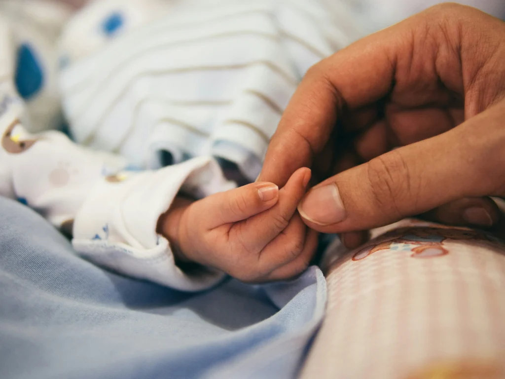 Parent holding baby’s hand gently, symbolizing care and justice sought with the best birth injury lawyer.